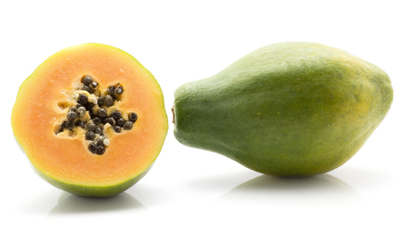 Green papaya (pawpaw, papaw) one whole one sliced half with seeds isolated on white backgroundの写真素材