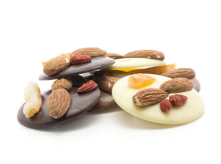 Melted chocolate circles stack (dark, milk and white varities) with two almonds, pineapple and berry, isolated on white backgroundの写真素材
