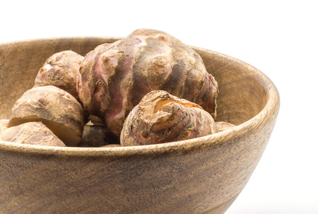 Jerusalem artichoke closeup in a wooden bowl isolated on white background sweet crisp topinambur