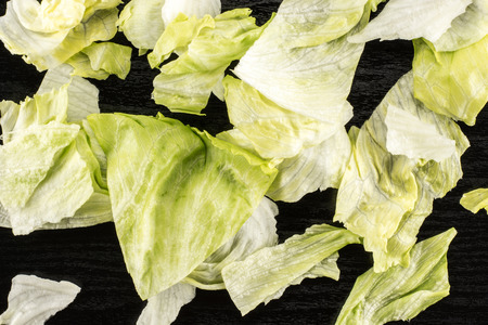 Iceberg lettuce fresh torn salad leaves table top isolated on black wood backgroundの写真素材