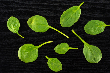Fresh baby spinach leaves top view on black wood backgroundの写真素材