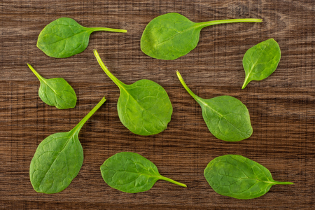 Fresh baby spinach leaves top view on brown wood backgroundの写真素材