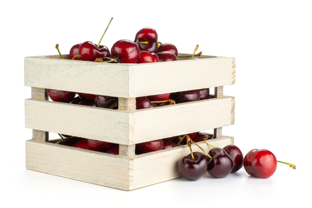 Sweet bright red cherry in a wooden box isolated on whiteの写真素材