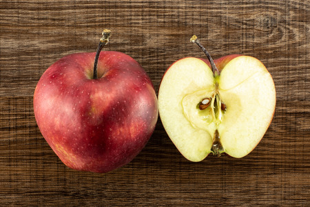 Red delicious one apple and section half flatlay on brown wood background