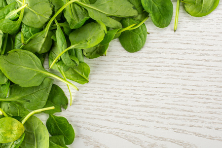 Fresh baby spinach leaves top view on grey wood background left upper corner
