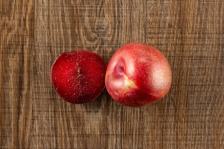 Group of one whole one half of fresh pluot interspecific plums variety flatlay on brown woodの写真素材