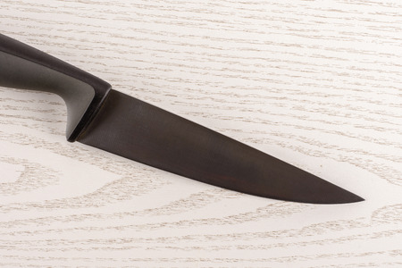 One whole kitchen tool stainless steel chef knife with grey plastic handle flatlay on grey wood