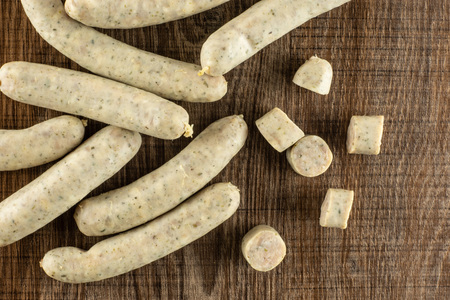 Lot of whole lot of slices lot of pieces of bavarian white sausage stack flatlay on brown woodの写真素材