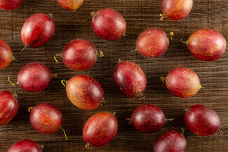 Lot of whole fresh red gooseberry hinnomaki variety flatlay on brown woodの写真素材