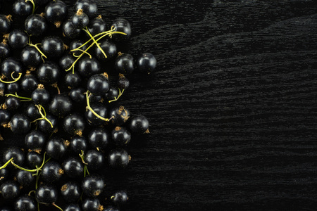 Lot of whole fresh black currant berry ben gairn variety left corner flatlay on black woodの写真素材