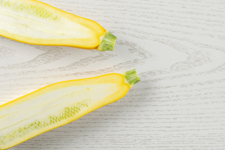 Group of two halves of raw yellow zucchini flatlay on grey woodの写真素材