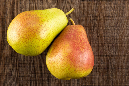 Group of two whole fresh red pear forelle variety flatlay on brown woodの写真素材