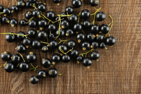 Lot of whole fresh black currant berry ben gairn variety left upper corner flatlay on brown woodの写真素材