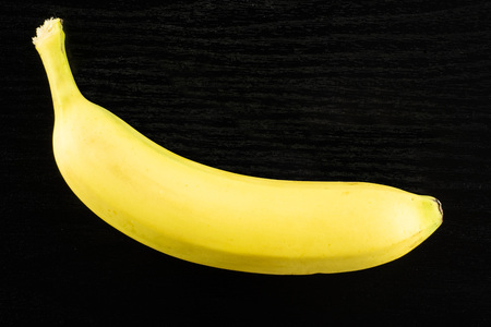 One whole fresh yellow banana flatlay on black woodの写真素材