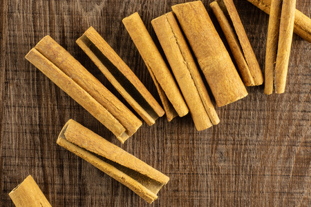 Lot of whole dry brown cinnamon stick flatlay on brown woodの写真素材