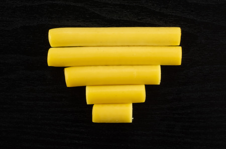 Group of five whole smoked slovak string cheese stick in line flatlay on black wood