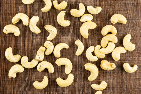 Lot of whole raw cashew nut flatlay on brown woodの写真素材
