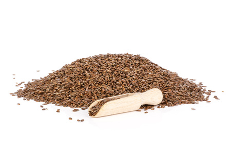 Pile of lot of whole fresh brown flaxseeds with wooden scoop isolated on white backgroundの写真素材