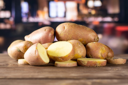 Group of lot of whole two halves three slices of fresh red potato francelina variety with restaurant in backgroundの写真素材