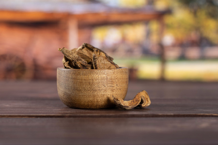Lot of slices of dry brown mushroom boletus edulis variety with wooden bowl with cart in backgroundの写真素材