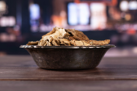 Lot of slices of edible dry brown mushroom boletus edulis variety in old iron bowl with restaurant in backgroundの写真素材