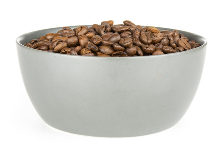 Lot of whole dark brown coffee beans sweet arabica variety in a grey ceramic bowl isolated on white backgroundの写真素材