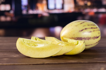 Group of one whole three slices of fresh striped pepino melon with restaurant in backgroundの写真素材
