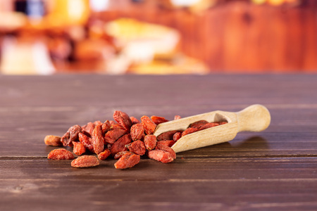 Lot of whole dried red goji berries with wooden scoop with rustic wood kitchen in backgroundの写真素材