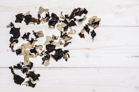 Lot of slices of dry black mushroom jew ear variety left upper corner flatlay on white woodの写真素材