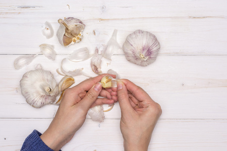 Woman hands are spliting garlic cloves. recipe step by step baked potatoes with onion flatlay on white woodの写真素材