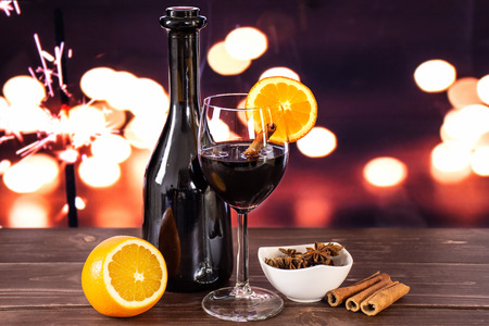 Glass of hot wine with oranges and a bottle, ready to drink. recipe step by step hot red mulled wine with lights in dark backgroundの写真素材