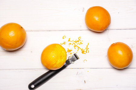 Scraping orange zest with a peeler. recipe step by step hot red mulled wine flatlay on white woodの写真素材