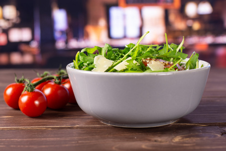Ready to eat. recipe step by step arugula salad in a grey ceramic bowl with restaurant in backgroundの写真素材
