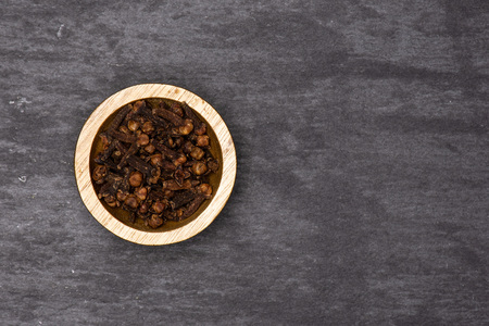 Lot of whole small dried cloves spice with wooden bowl flatlay on grey stoneの写真素材
