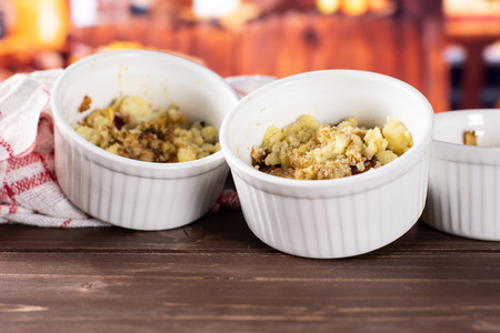 Recipe step by step crumble with fruits two servings in a ceramic ramekin with rustic wood kitchen in backgroundの写真素材
