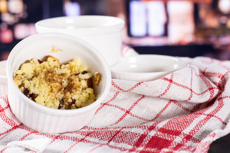 Recipe step by step crumble with fruits one serving closeup in a ceramic ramekin with restaurant in backgroundの写真素材