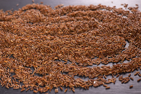 Lot of whole raw red rice on grey stoneの写真素材