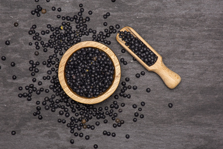 Lot of whole black lentils beluga variety scoop with wooden bowl flatlay on grey stoneの写真素材