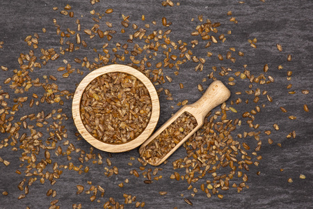 Lot of whole raw bulgur grains in a scoop with wooden bowl flatlay on grey stoneの写真素材