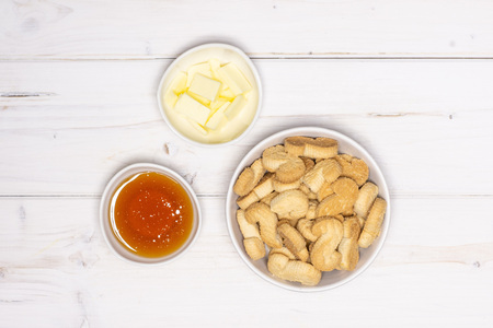 Mix shortbread, butter and honey. recipe step by step no bake cheesecake flatlay on white woodの写真素材