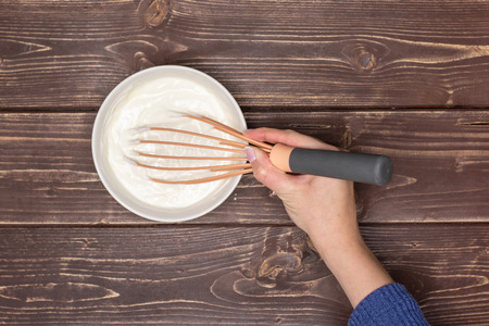 Woman hand is mixing cottage and a sour cream. recipe step by step no bake cheesecake flatlay on...