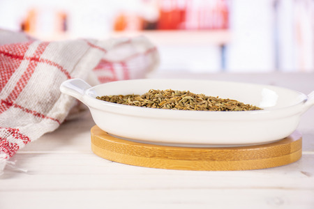 Lot of whole dry roman caraway seeds in a ceramic stewpan in a white kitchenの写真素材