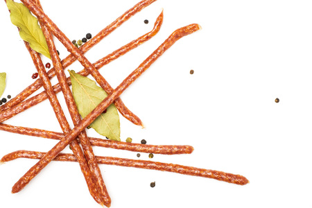 Lot of whole spicy salami stick tyrolini with black pepper and bay leaf flatlay isolated on white...