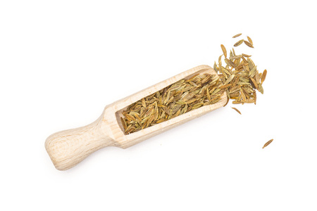 Lot of whole roman caraway seeds with wooden scoop flatlay isolated on white background