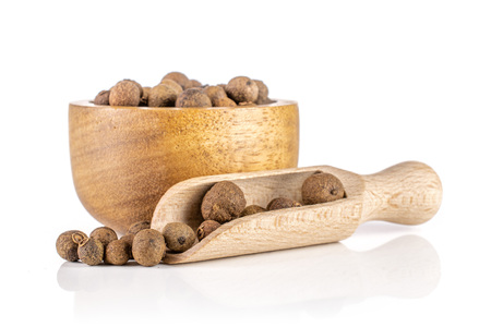 Lot of whole dry brown allspice berries with wooden bowl and wooden scoop isolated on white backgroundの写真素材