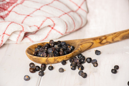 Lot of whole dry juniper berry seed on white woodの写真素材