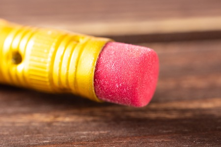 Closeup of one piece of yellow pencil cup eraser on brown woodの写真素材