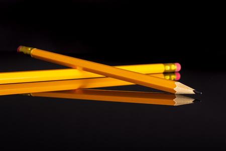 Group of two whole yellow pencil isolated on black glass
