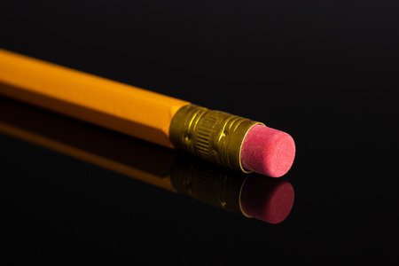 One whole yellow pencil cup eraser isolated on black glassの写真素材