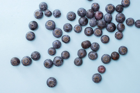 Lot of whole fresh sweet purple blueberry american flatlay isolated on blue pastel background